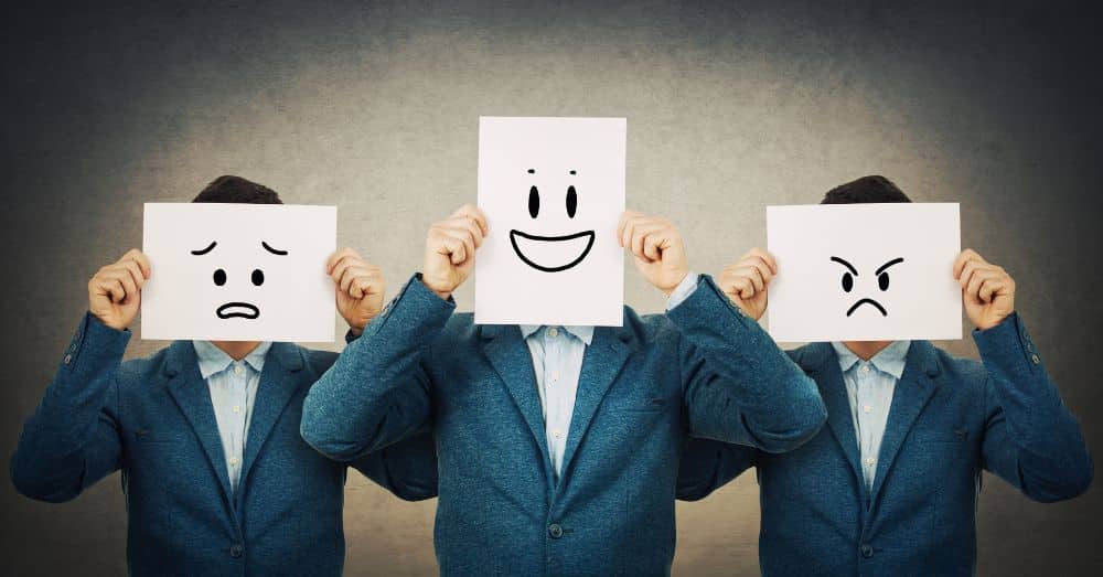 three men holding white papers with hand-drawn faces