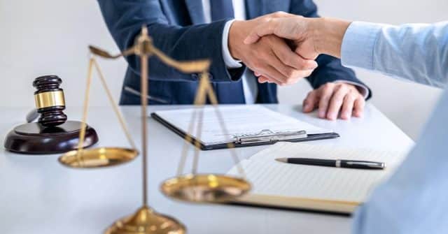 two professional people shaking hands with scale and gavel