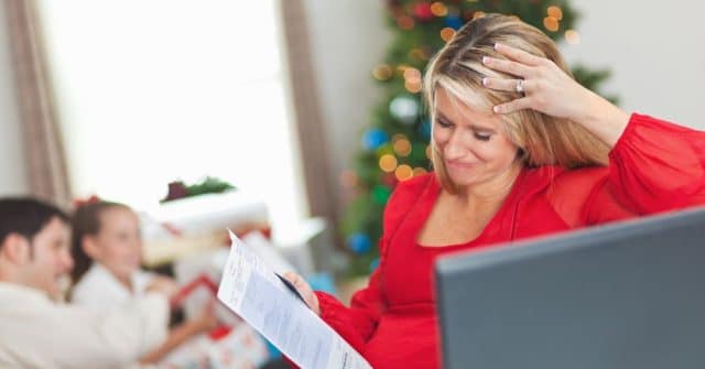 woman with bill in front of family and christmas tree