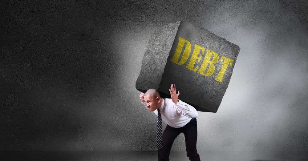 man holding giant stone with debt written on it